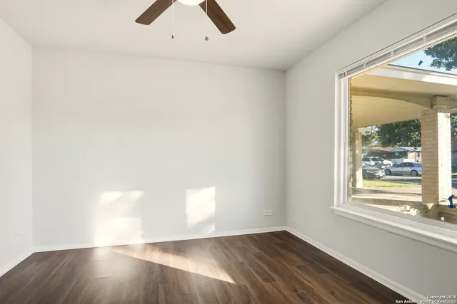 an empty room with wooden floor and windows