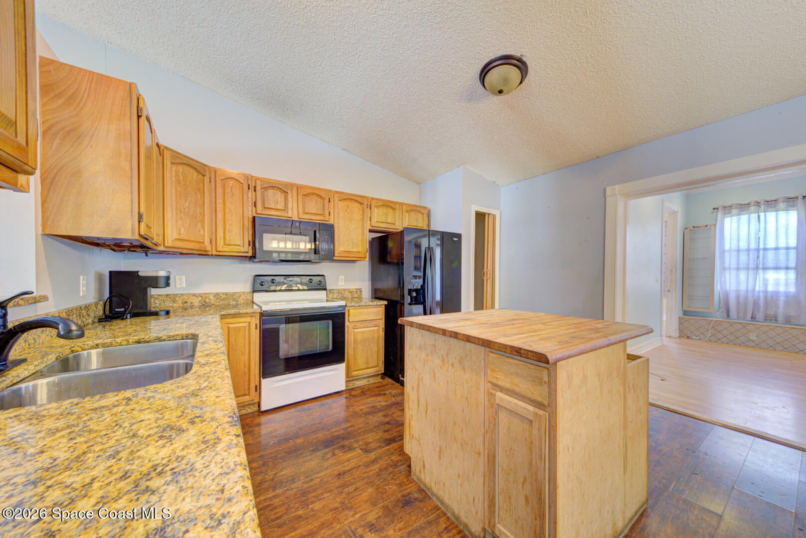 1090 Castile Road Southeast Palm Bay, FL 32909 - Photo 4 of 23 a kitchen with stainless steel appliances granite countertop a stove top oven a sink dishwasher and a refrigerator with wooden floor