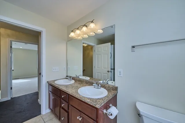 a bathroom with a granite countertop sink a toilet and a mirror
