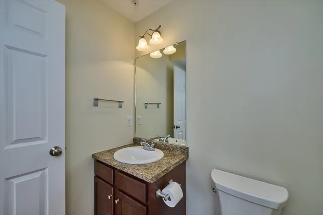 a bathroom with a granite countertop sink a toilet and a mirror