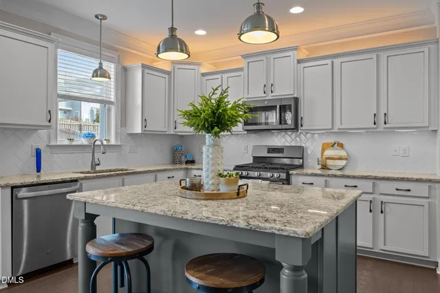 a kitchen with stainless steel appliances granite countertop a sink a stove a refrigerator and chairs