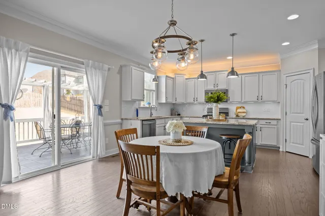 a kitchen with center island a sink dishwasher a dining table and chairs with wooden floor