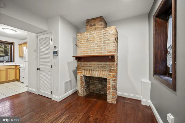 an empty room with wooden floor fireplace and windows