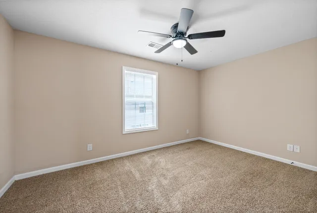 an empty room with a window and a fan