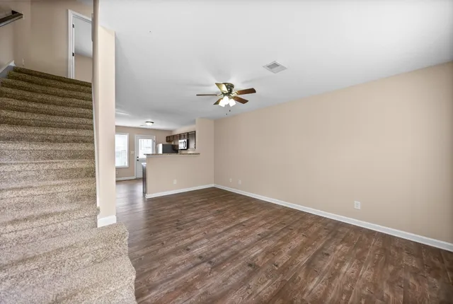 a view of a livingroom with wooden floor and a ceiling fan