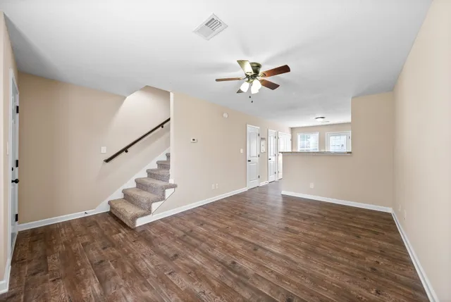 wooden floor in an empty room with a window and a ceiling fan