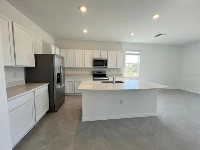 a kitchen with granite countertop white cabinets and stainless steel appliances