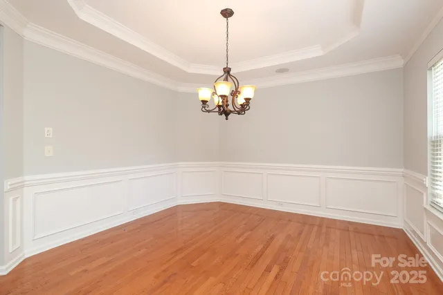 a view of a room with wooden floor and chandelier