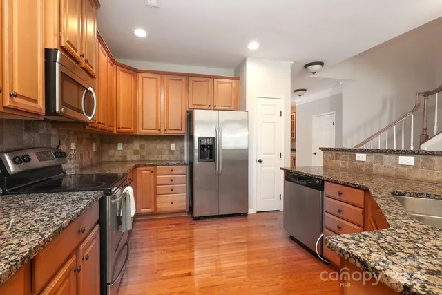 a kitchen with stainless steel appliances granite countertop a refrigerator a stove and a sink