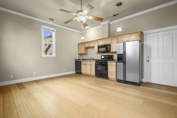 a view of a kitchen with a sink stainless steel appliances wooden floor and a window