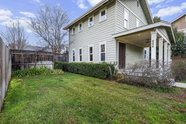 a view of a house with brick walls and a yard with plants