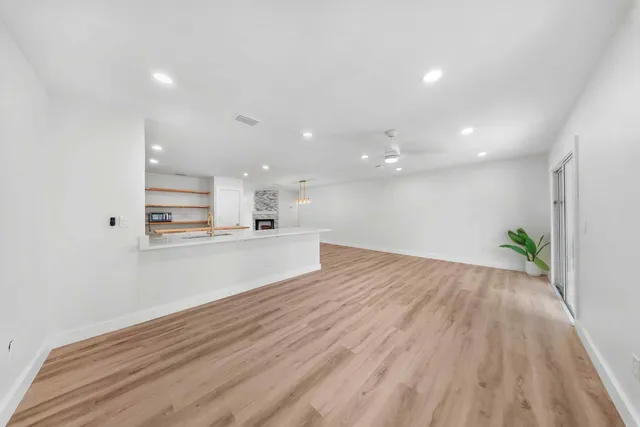 a view of a kitchen with kitchen island wooden floor stainless steel appliances and cabinets