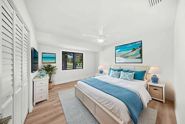 a bedroom with a large bed a painting on the wall and a large window