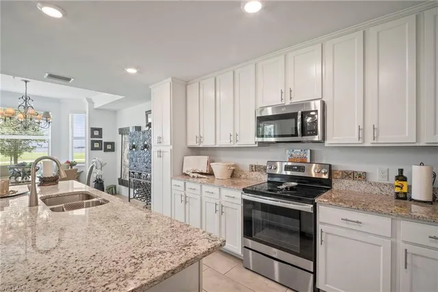 a kitchen with stainless steel appliances kitchen island granite countertop a stove top oven a sink a refrigerator and white cabinets