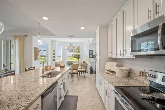 a kitchen with granite countertop a sink a counter top space stainless steel appliances and cabinets