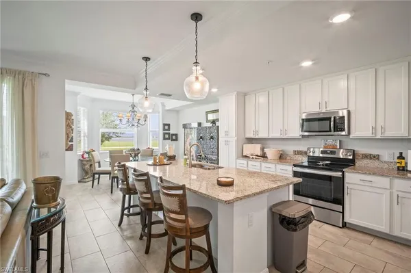 a kitchen with stainless steel appliances a table chairs sink and cabinets