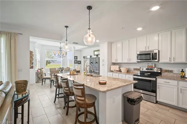 a kitchen with stainless steel appliances a table chairs sink and cabinets