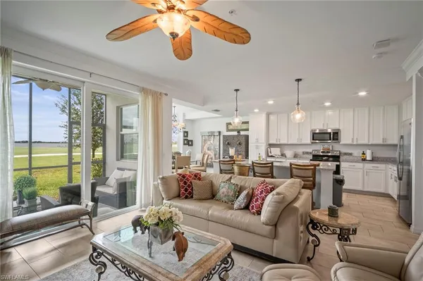 a living room with furniture kitchen view and a large window