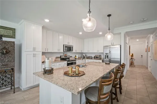 a kitchen with sink a refrigerator and chairs