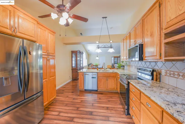 a large kitchen with stainless steel appliances granite countertop a refrigerator a oven a stove and a wooden floors