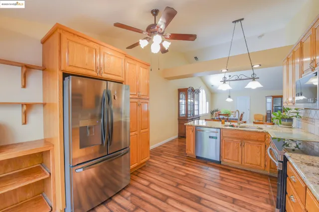 a kitchen with stainless steel appliances granite countertop a refrigerator a stove and a wooden floors
