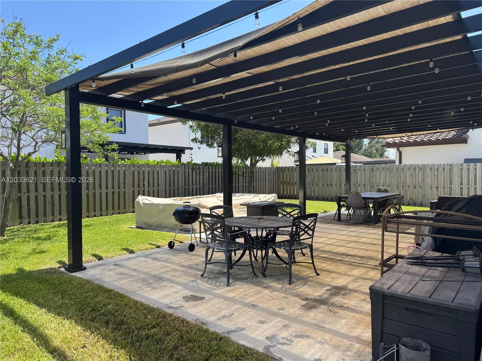 11942 Southwest 243rd Street Homestead, FL 33032 - Photo 36 of 50 a view of a patio with table and chairs under an umbrella with a small yard