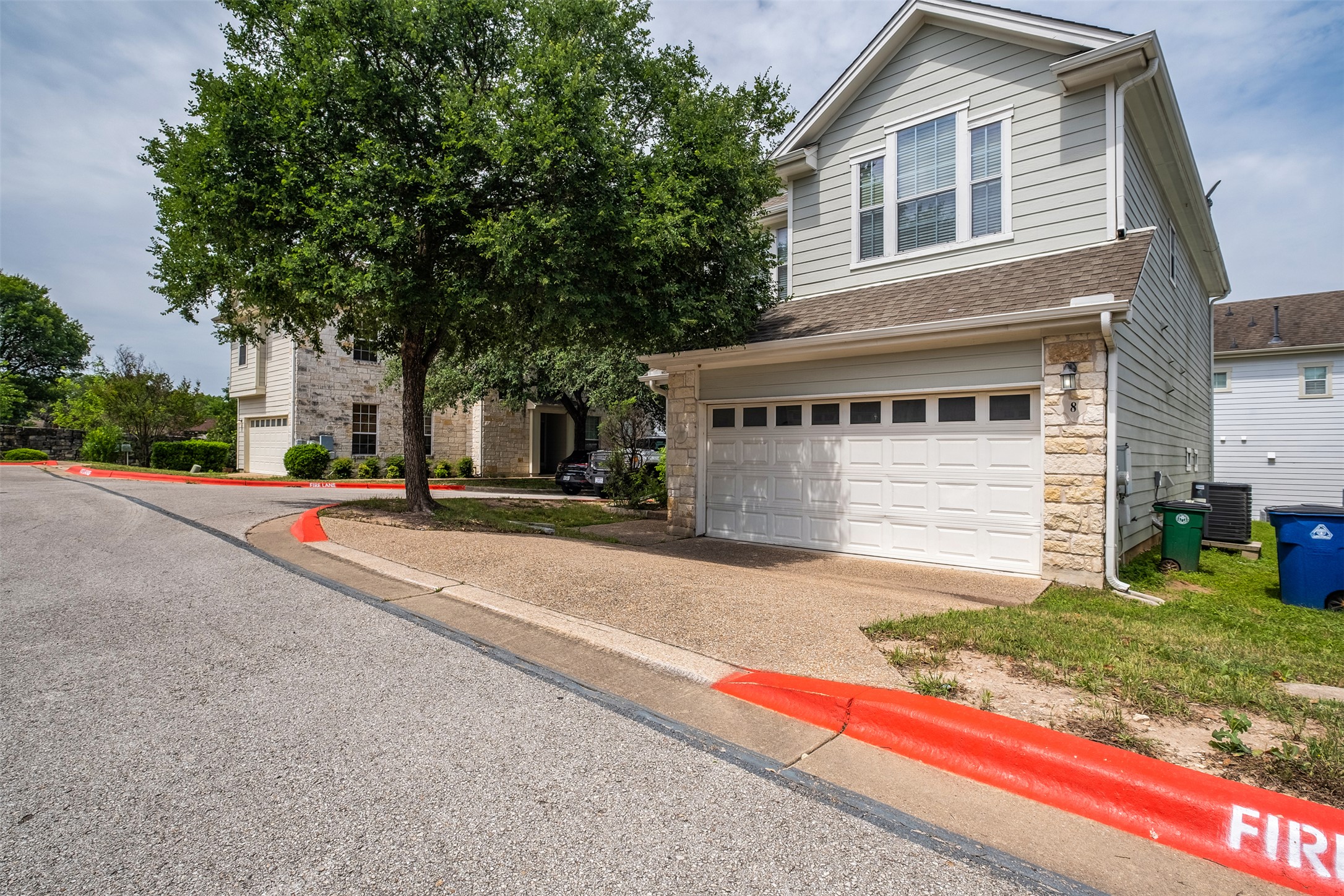 6715 Windrift Way, Unit 8 Austin, TX 78745 - Photo 3 of 24 A traditional two-story home features a spacious garage and ample driveway parking.