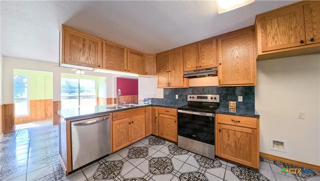 a kitchen with stainless steel appliances granite countertop a stove a sink and a microwave