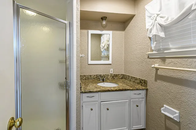 a bathroom with a granite countertop sink a mirror and a shower