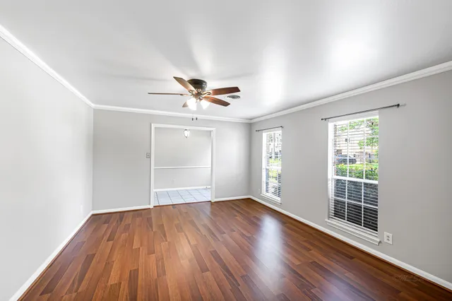 a view of empty room with wooden floor and fan