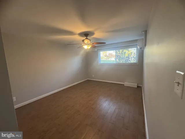 an empty room with windows and chandelier fan
