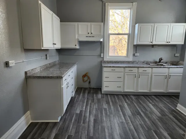 a kitchen with granite countertop wooden cabinets appliances a sink and a window