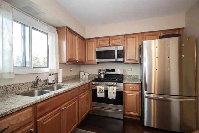a kitchen with stainless steel appliances granite countertop a refrigerator stove and sink