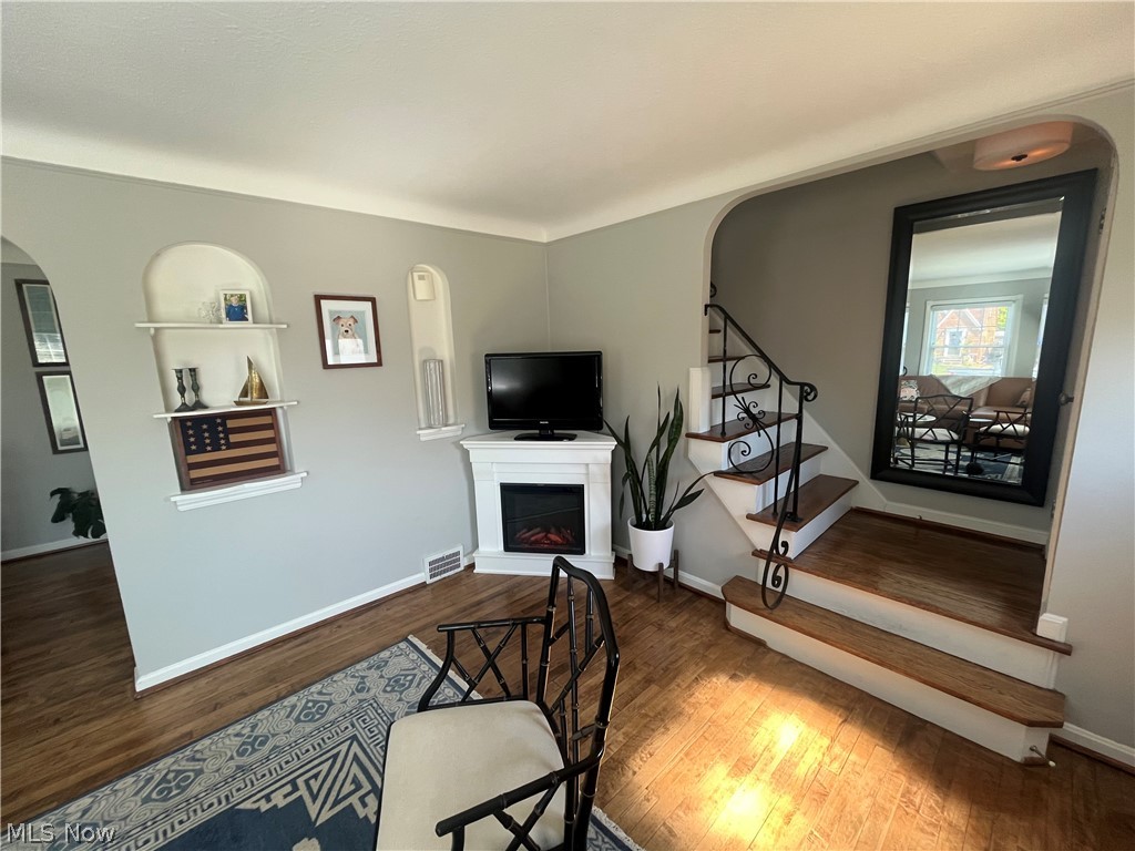 3471 Warren Road Cleveland, OH 44111 - Photo 7 of 17 Living room with arched walkways, stairway, a fireplace with raised hearth, and wood finished floors