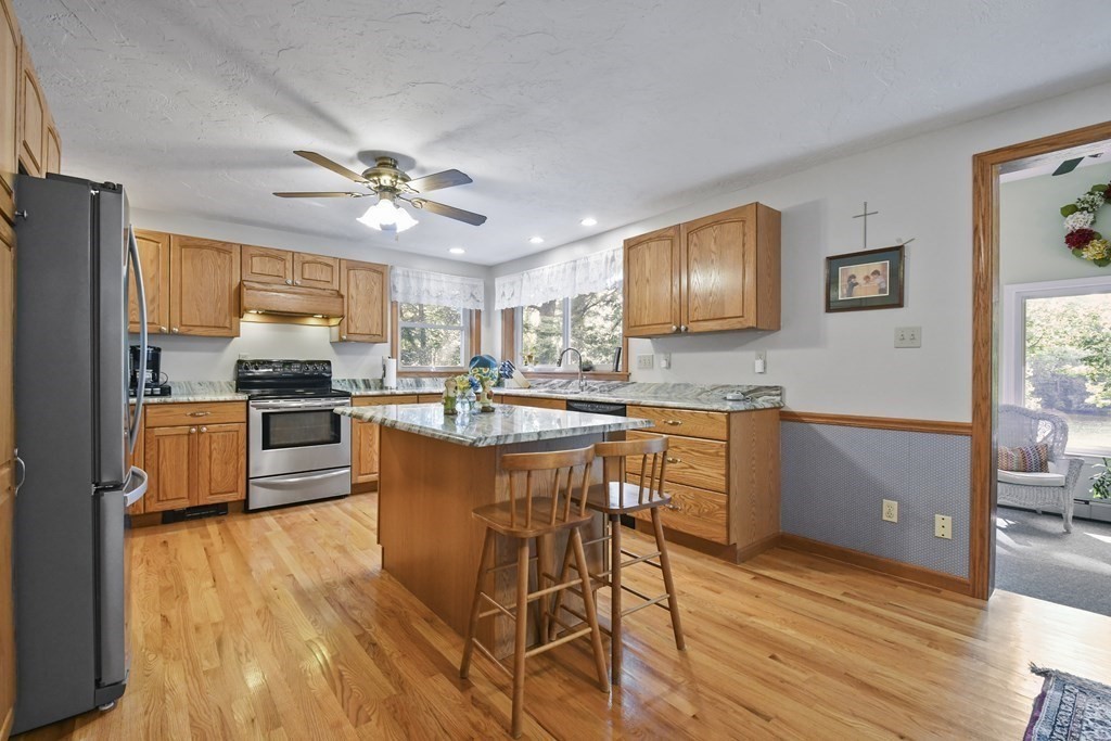 60 Lincoln Point Road Charlton, MA 01507 - Photo 13 of 42 a kitchen with stainless steel appliances granite countertop wooden floors stove top oven with a dining table and chairs