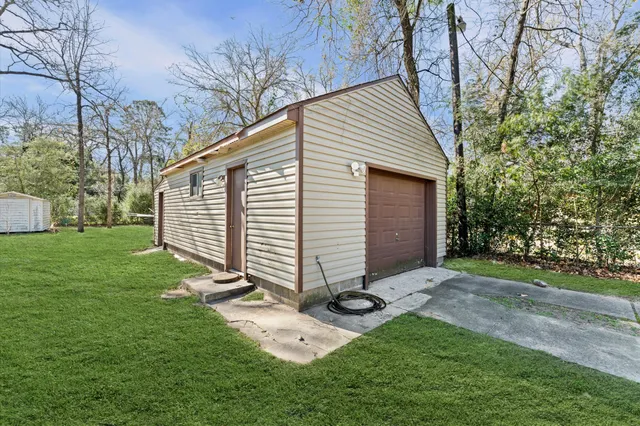 a view of a white house with a small yard and large tree