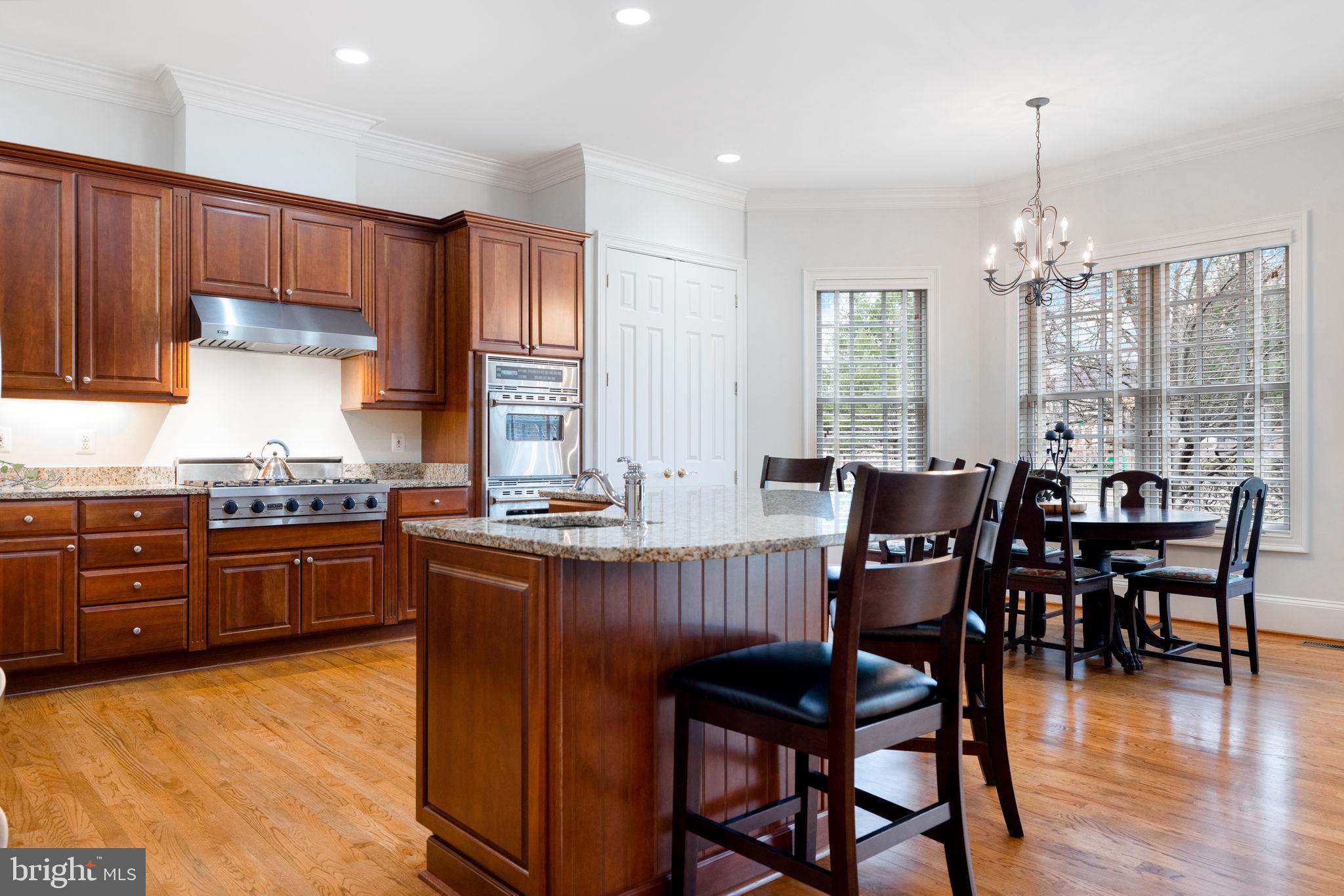 41741 Raspberry Drive Leesburg, VA 20176 - Photo 55 of 117 a kitchen with granite countertop a table chairs stove and cabinets