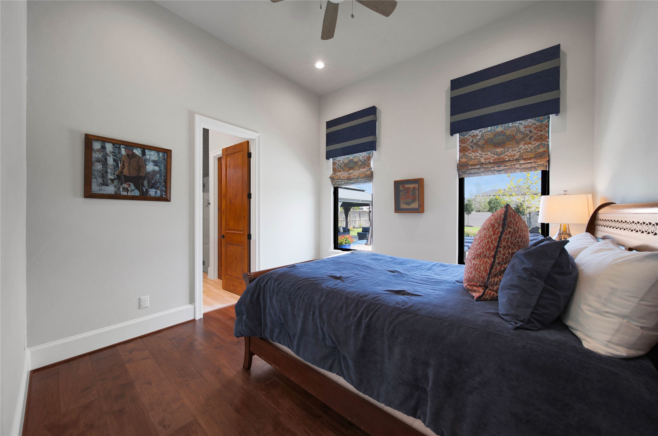24718 Shadow Pond Spring, TX 77389 - Photo 31 of 49 Cozy bedroom with hardwood floors, a stylish wood door, and large windows adorned with elegant blinds, offering ample natural light.