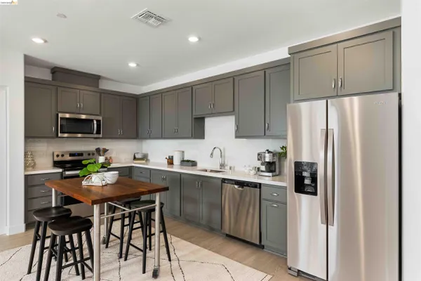 a kitchen with stainless steel appliances a refrigerator a sink a stove a table and chairs