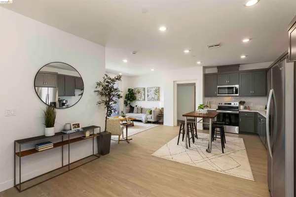 a living room with furniture a mirror kitchen view and a wooden floor
