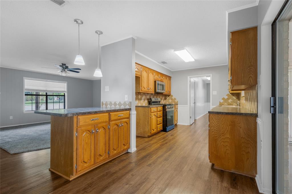 1609 Robin Street Mineola, TX 75773 - Photo 7 of 24 Kitchen featuring wood-finish flooring, wood cabinetry, granite-style countertops, and a tiled backsplash