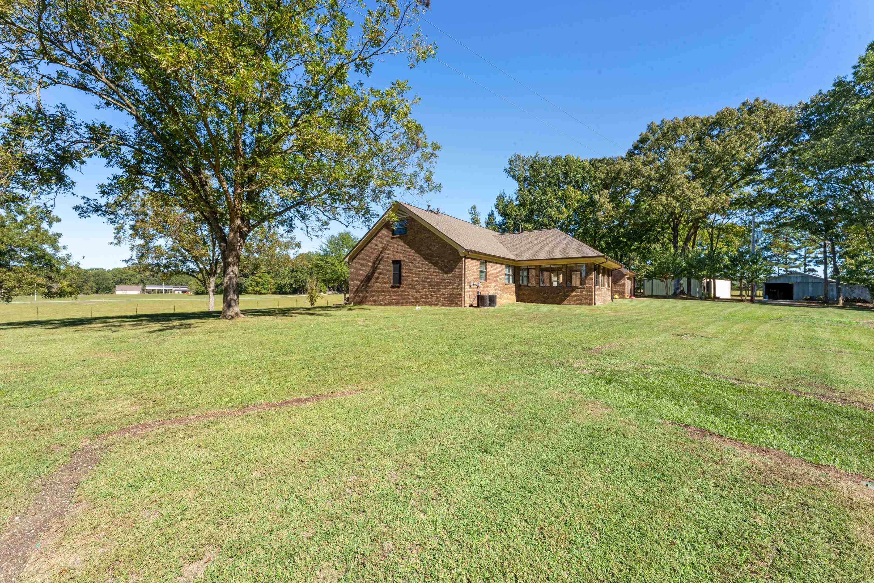 650 Blain Road Rossville, TN 38066 - Photo 23 of 26 This rear view of the home showcases a small portion of the expansive property, with the show and barn visible in the distance. The setting highlights both functionality and serenity, offering endless possibilities for work, hobbies, or storage.