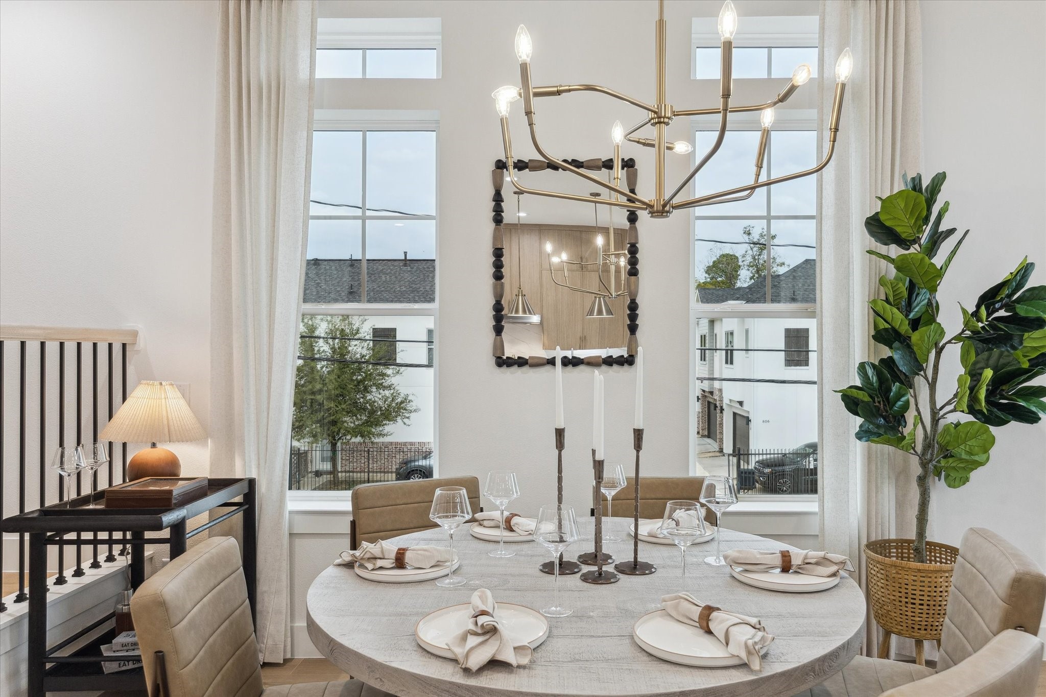 752 Curtin Street Houston, TX 77018 - Photo 10 of 37 Elegant dining area featuring a round table set for four, under a striking modern chandelier. Large windows provide ample natural light, complemented by tasteful decor and a lush potted plant for a welcoming ambiance.