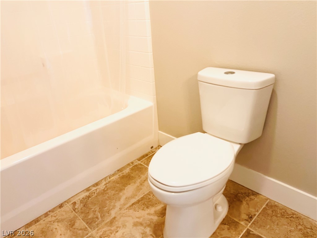 161 Dunblane Street Henderson, NV 89012 - Photo 40 of 56 Functional bathroom featuring a tub and a white toilet with a beige tile floor.