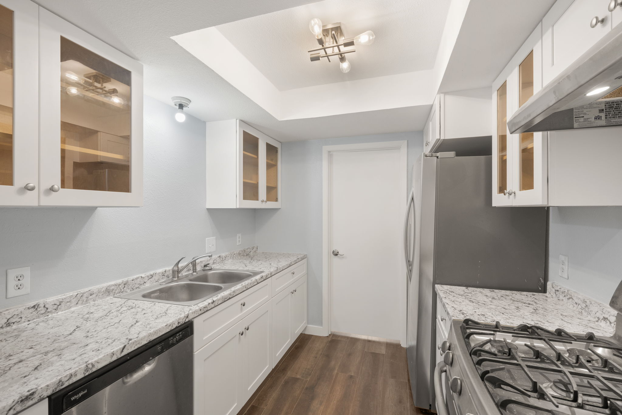 3917 Leafield Drive Austin, TX 78749 - Photo 25 of 40 Kitchen featuring glass insert cabinets, white cabinets, stainless steel appliances, dark wood-style floors, and a raised ceiling