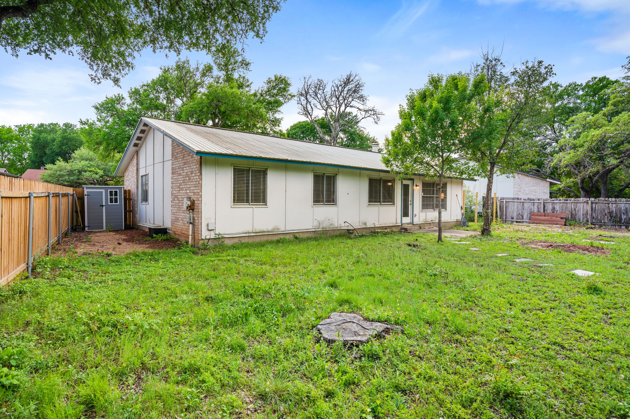 3917 Leafield Drive Austin, TX 78749 - Photo 34 of 40 Back of property featuring a fenced backyard, board and batten siding, a metal roof, brick siding, and an outbuilding