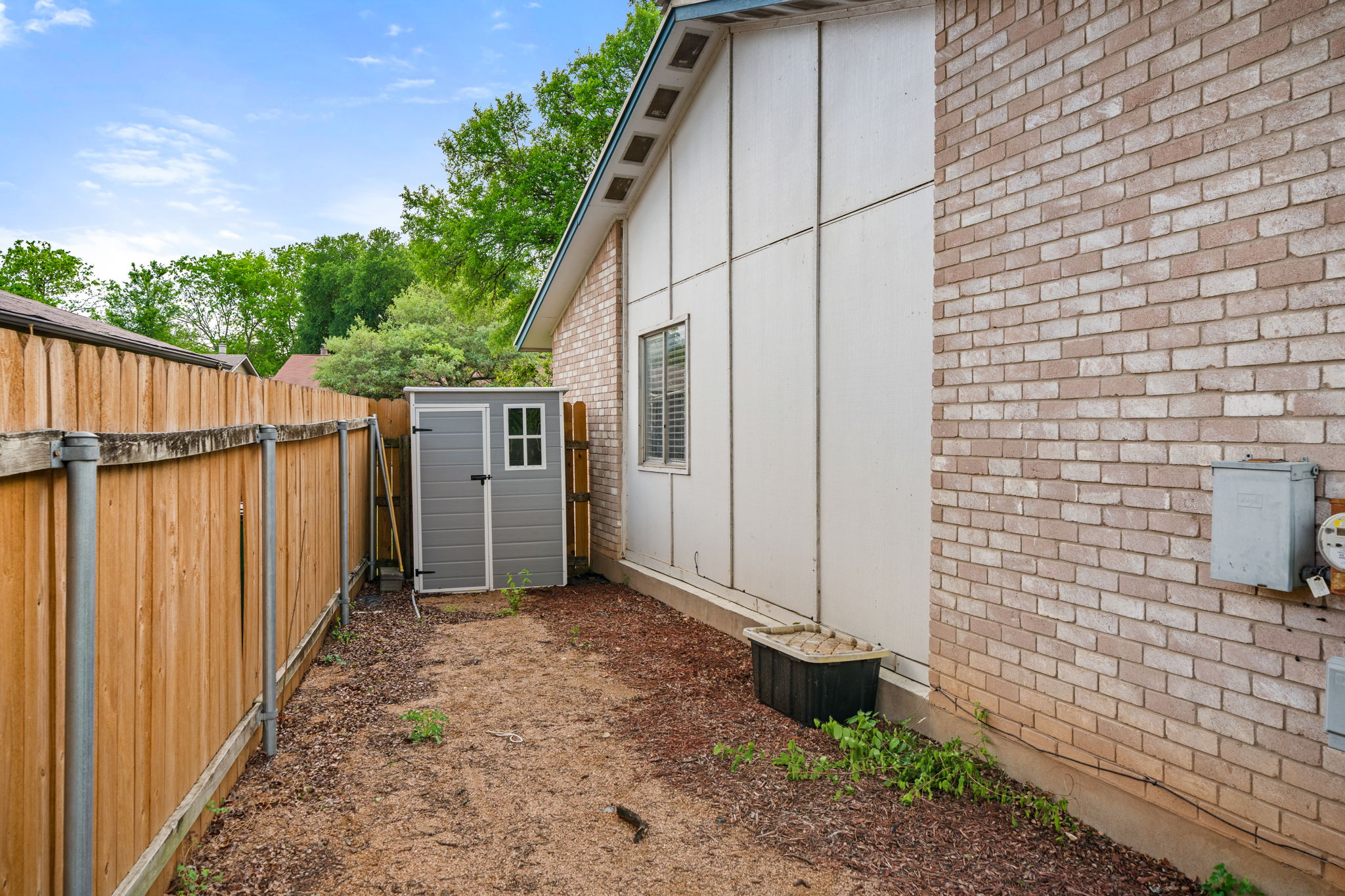 3917 Leafield Drive Austin, TX 78749 - Photo 37 of 40 View of side of home featuring brick siding, a storage unit, a fenced backyard, and board and batten siding