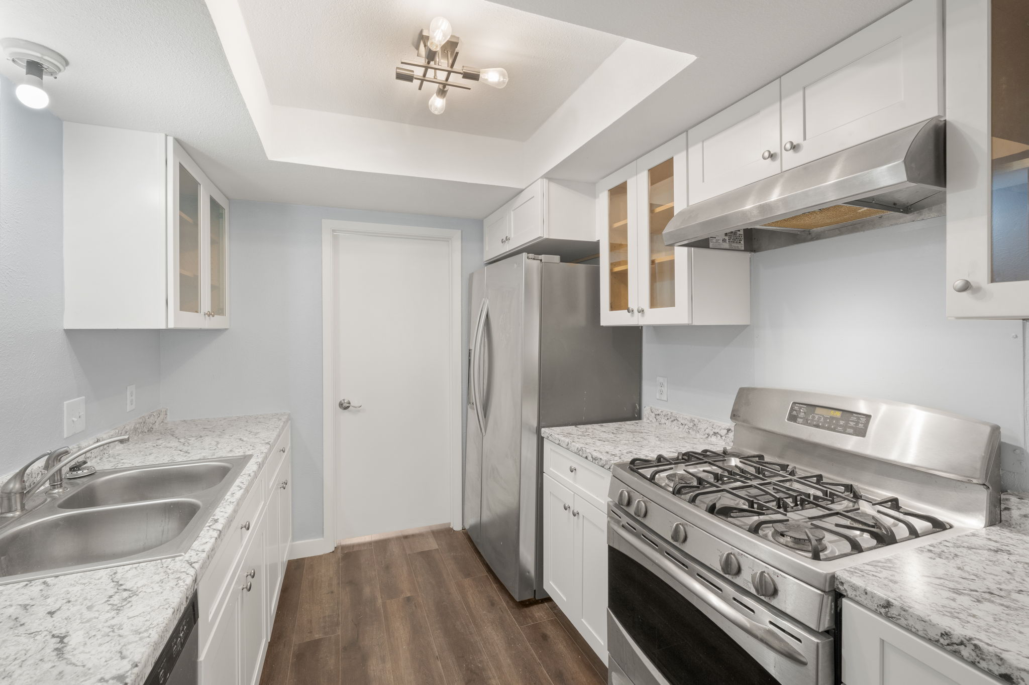 3917 Leafield Drive Austin, TX 78749 - Photo 5 of 40 Kitchen featuring glass fronted cabinets, stainless steel appliances, white cabinets, light countertops, and a tray ceiling