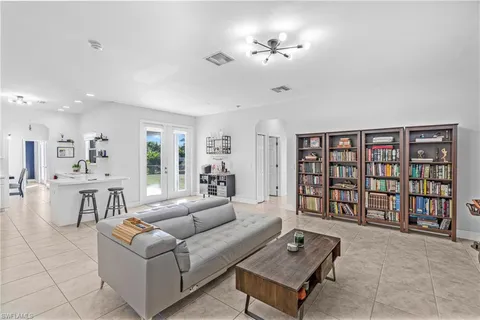 a living room with furniture and a dining table with bookshelf