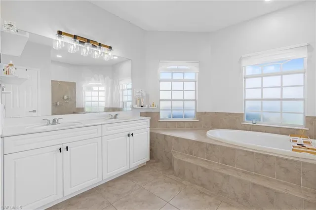 a spacious bathroom with a granite countertop double vanity sink a mirror and a bathtub